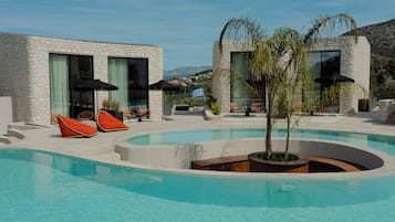 A pool area with lounge chairs and a view of the landscape.