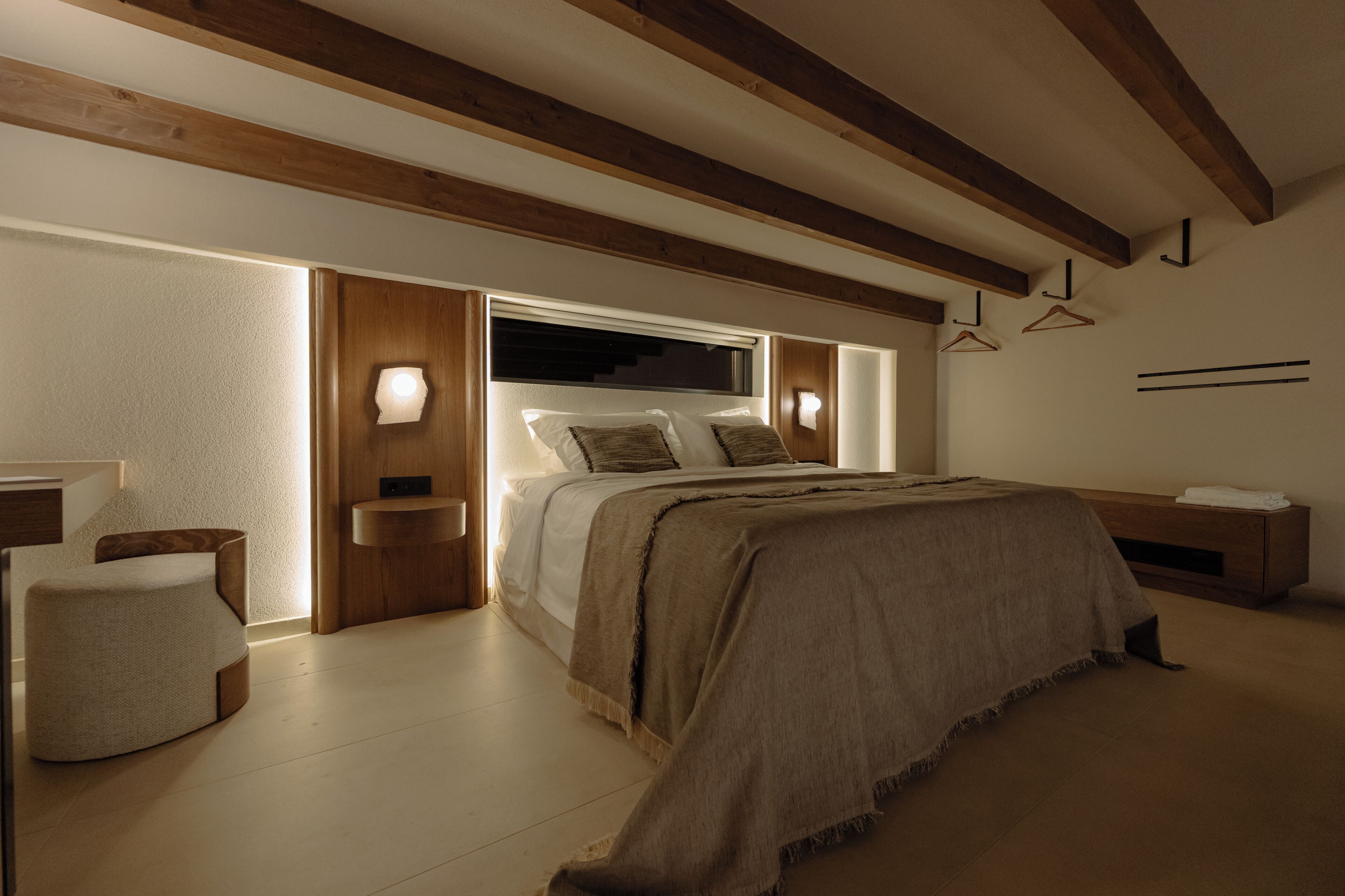 Une chambre à coucher avec un grand lit, des tables de chevet, une lampe de chevet, un luminaire suspendu et une tête de lit en bois.