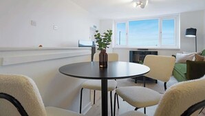 Ett modernt vardagsrum med ett runt bord, stolar, en soffa, en tv och ett fönster med utsikt.