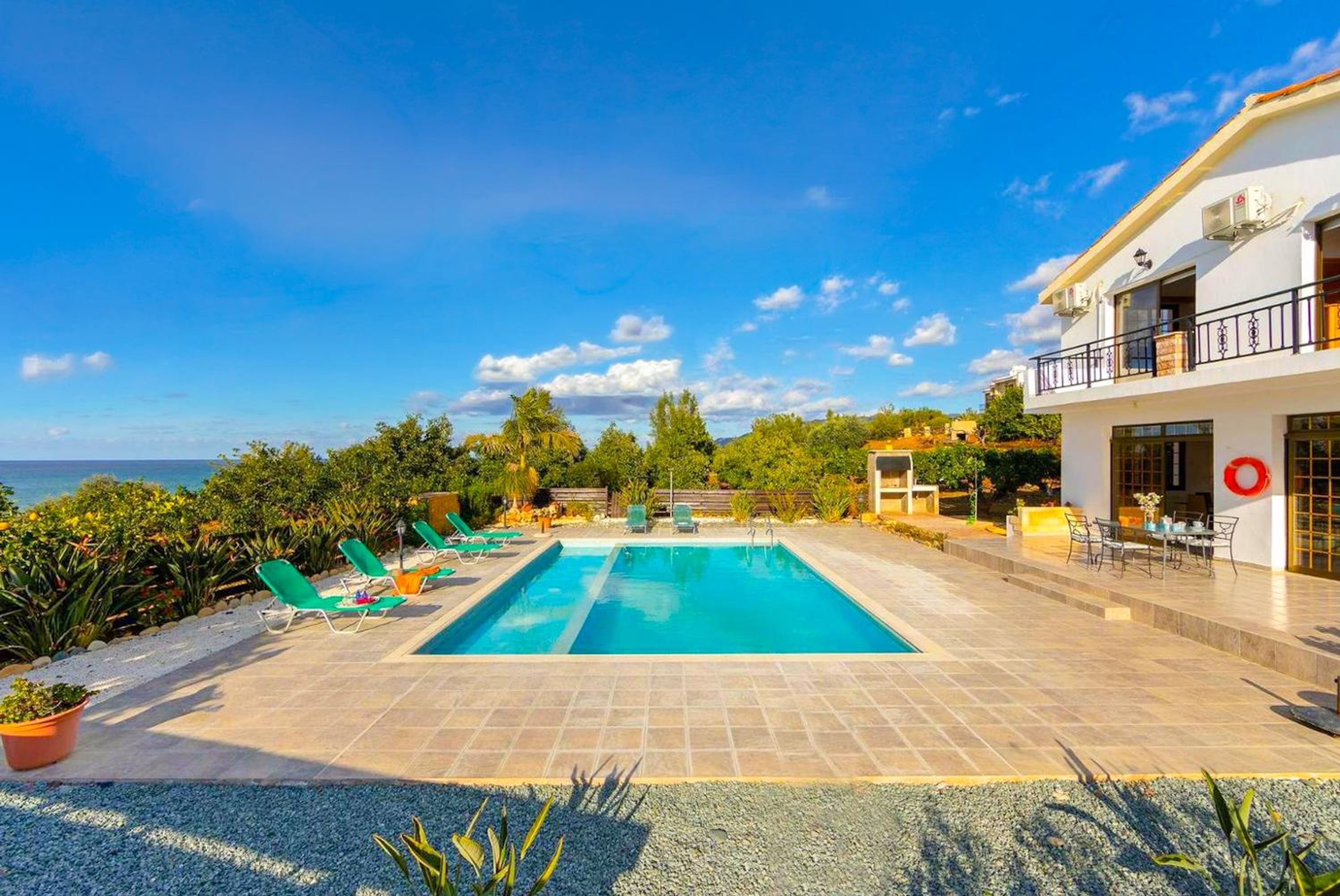Una piscina con sillas de descanso, un edificio con balcón y vistas al mar.