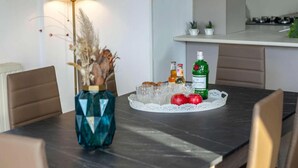 A dining table with a vase, a plate with apples, and bottles.