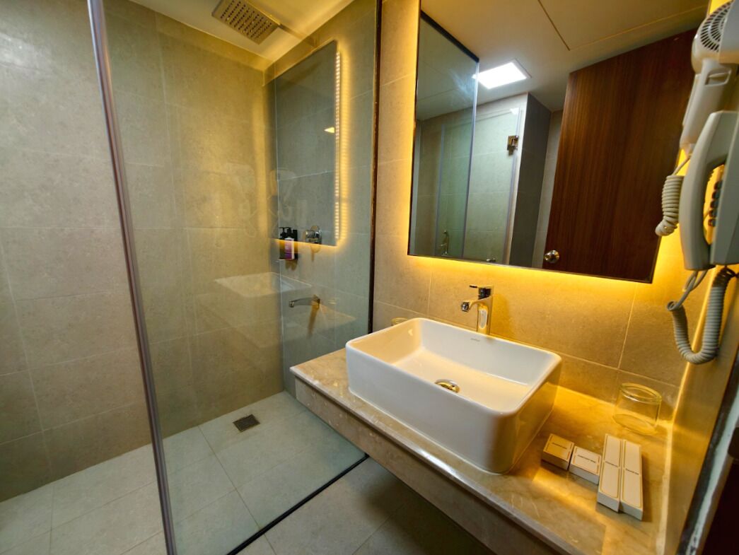 Une salle de bain moderne avec une douche à parois de verre, un lavabo blanc et un grand miroir.
