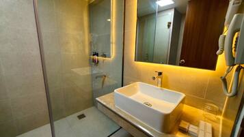 A modern bathroom with a glass-enclosed shower, a white sink, and a large mirror.