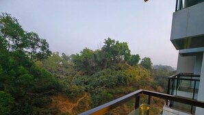 A balcony with a glass railing overlooking a forested area. - Hotel Grand Pacific (Cox's Bazar)
