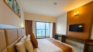 A hotel room with a large bed, a TV, a balcony, and a painting on the wall. - Hotel Grand Pacific (Cox's Bazar)