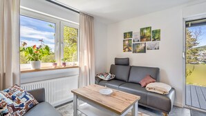 A modern living room with a sofa, a coffee table, and a window with potted plants. - Apartment 'Burgquartier' with Balcony and Wi-Fi (Schmallenberg)