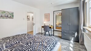 A bedroom with a bed, a desk, a chair, a wardrobe, and a window. - Apartment 'Burgquartier' with Balcony and Wi-Fi (Schmallenberg)