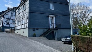 A large two-story building with a dark exterior, a visible entrance with a door and steps, and a street lamp to the right. - Apartment 'Burgquartier' with Balcony and Wi-Fi (Schmallenberg)
