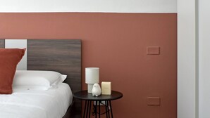 Una habitació d'hotel amb un llit, una taula rodona petita amb una làmpada i una vetust.