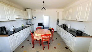 Una cocina compacta con armarios blancos, microondas, cocina y comedor con mesa y sillas.