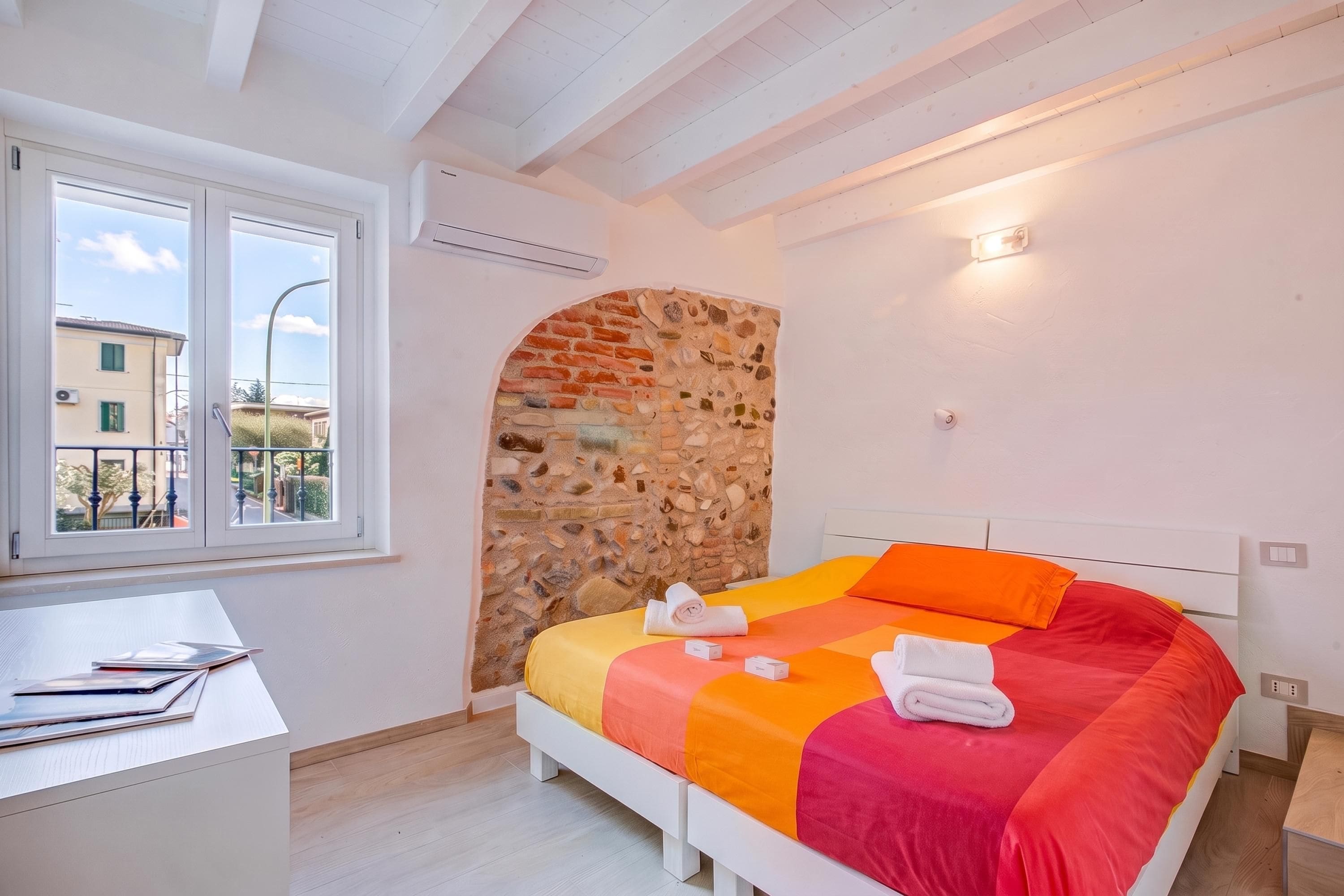 Un dormitorio con cama, escritorio y ventana.