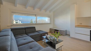 A modern living room with a sectional sofa, a coffee table, and a view through large windows.