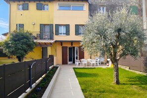 A residential building with a balcony, a small garden with a tree, and a patio area with outdoor furniture. - Peschiera Apartments Near The Lake (Peschiera del Garda)