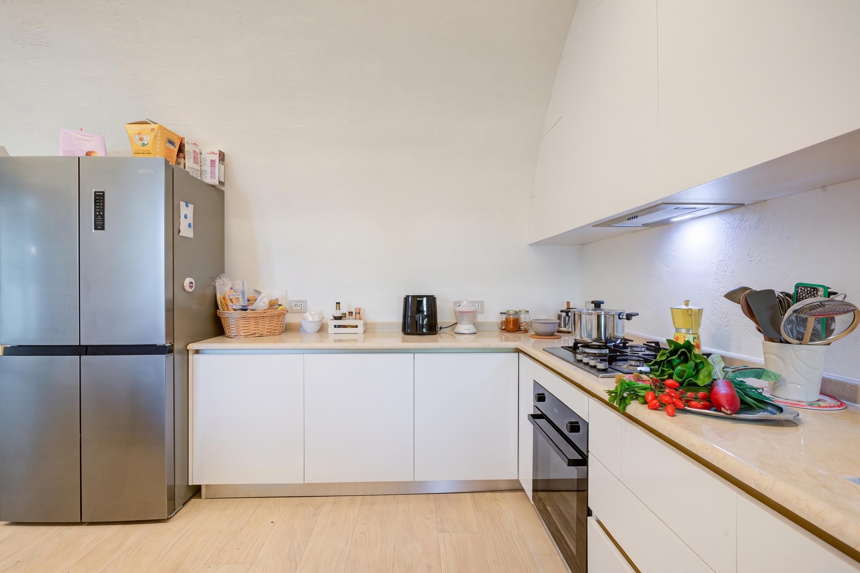 Una cocina moderna con un refrigerador de acero inoxidable, una cafetera y varios utensilios de cocina sobre la encimera.