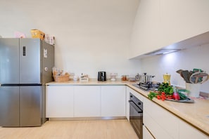 Una cocina moderna con un refrigerador de acero inoxidable, una cafetera y varios utensilios de cocina sobre la encimera.
