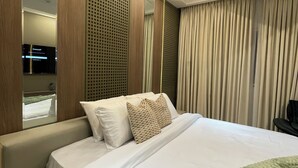 Ein Hotelzimmer mit einem großen Bett, einer Sitzecke, einem Fernseher und einem durch einen Spiegel sichtbaren Badezimmer.