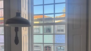 Una habitación de esquina con ventanal saliente, un radiador blanco y una lámpara colgante.