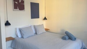 Un dormitorio con una cama, dos lámparas de pared y dos obras de arte abstracto en las paredes.