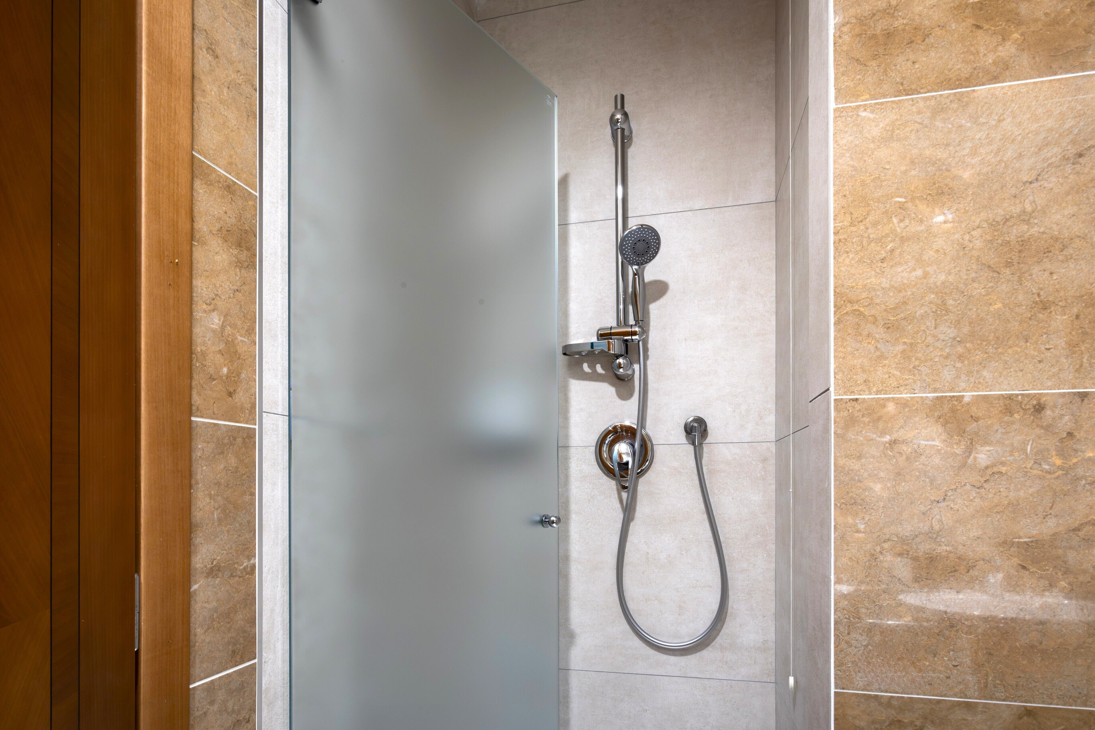 Een douche met een handdouche en een kraan op de muur.