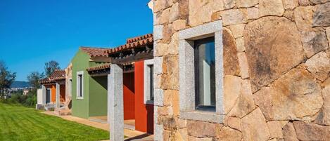 Una hilera de edificios de paredes de piedra con ventanas, cielo despejado y un césped bien cuidado.