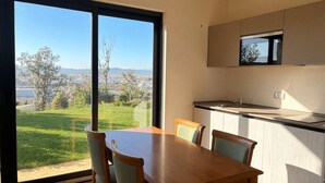 A modern kitchen with a large window, a dining table with chairs, and a view of a cityscape. - Suites Del Borgo (Olbia)