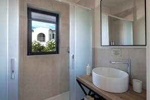 A modern bathroom with a large window, a white sink, and a mirror. - Suites Del Borgo (Olbia)