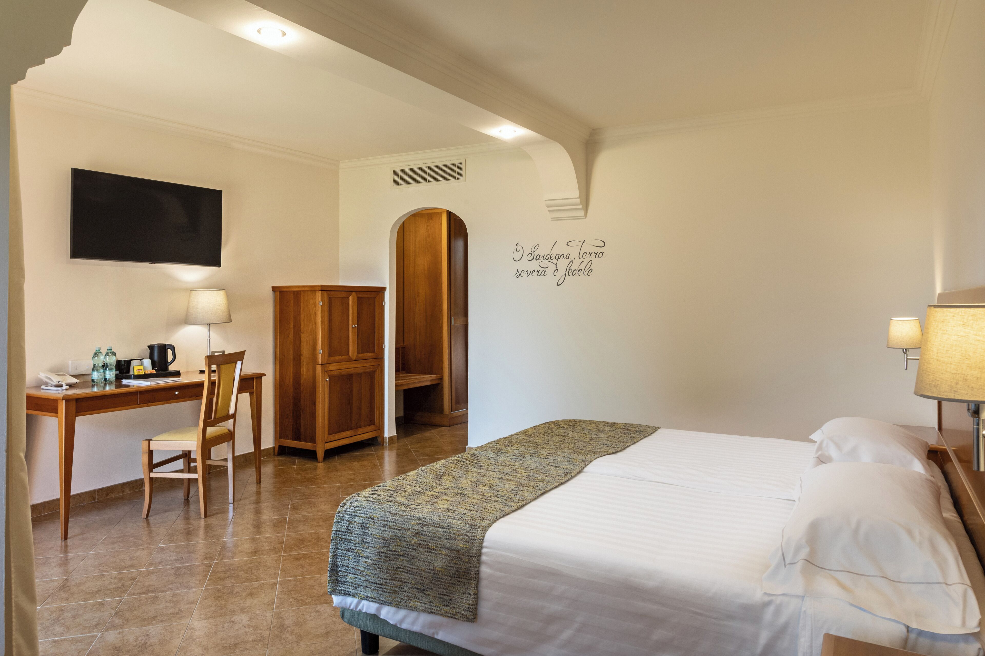 Ein Hotelzimmer mit Bett, Schreibtisch, Stuhl, Kleiderschrank und einer Wand mit einer dekorativen Inschrift.