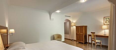 A hotel room with a bed, a desk, a chair, and a wardrobe.