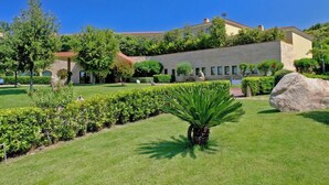 A building with a flat roof, surrounded by well-maintained hedges and a large rock. - Suites Del Borgo (Olbia)