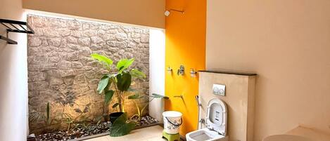 A bathroom with a stone wall, a toilet, a sink, and a shower area.