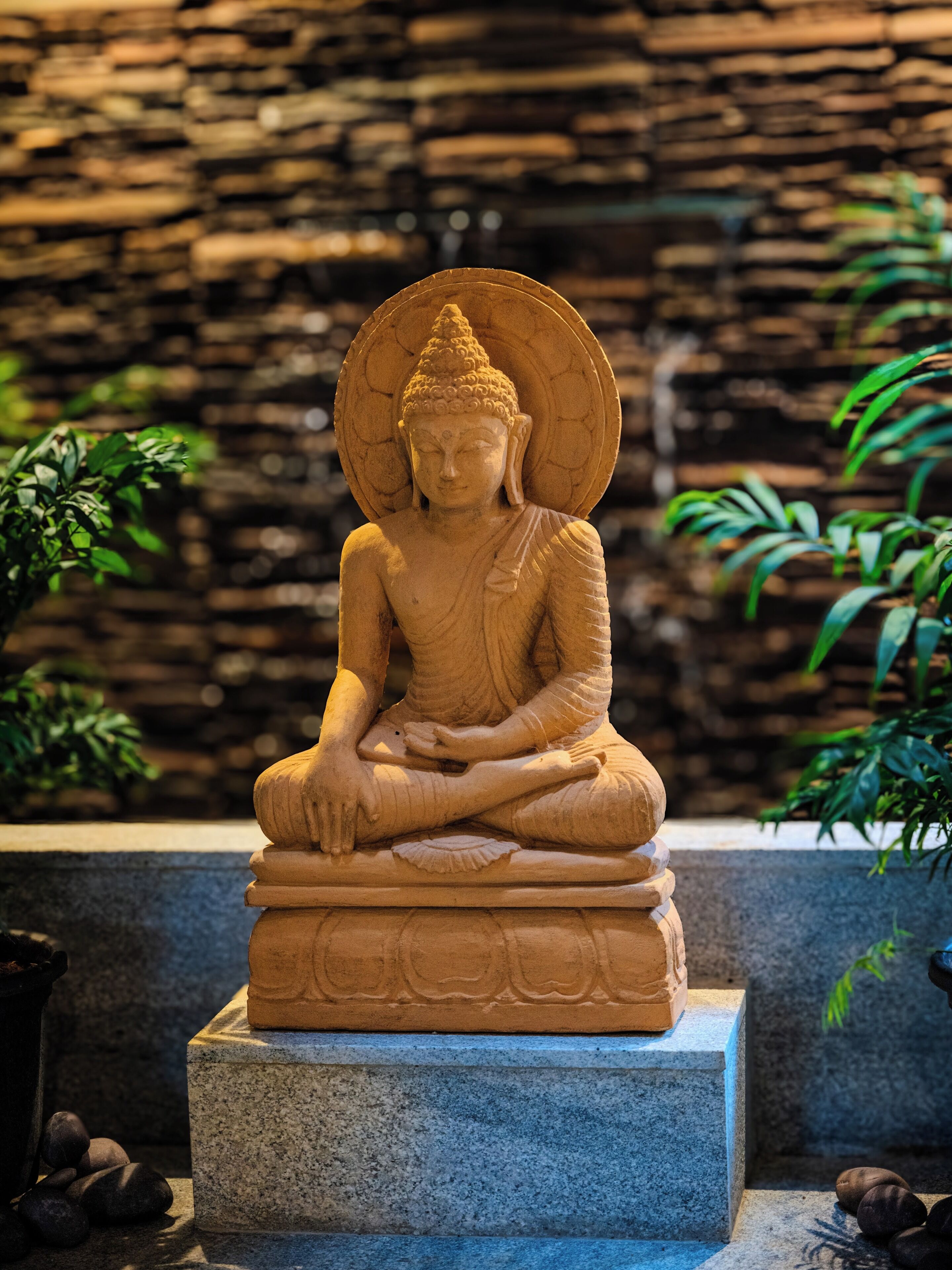 A seated Buddha statue on a stone pedestal.