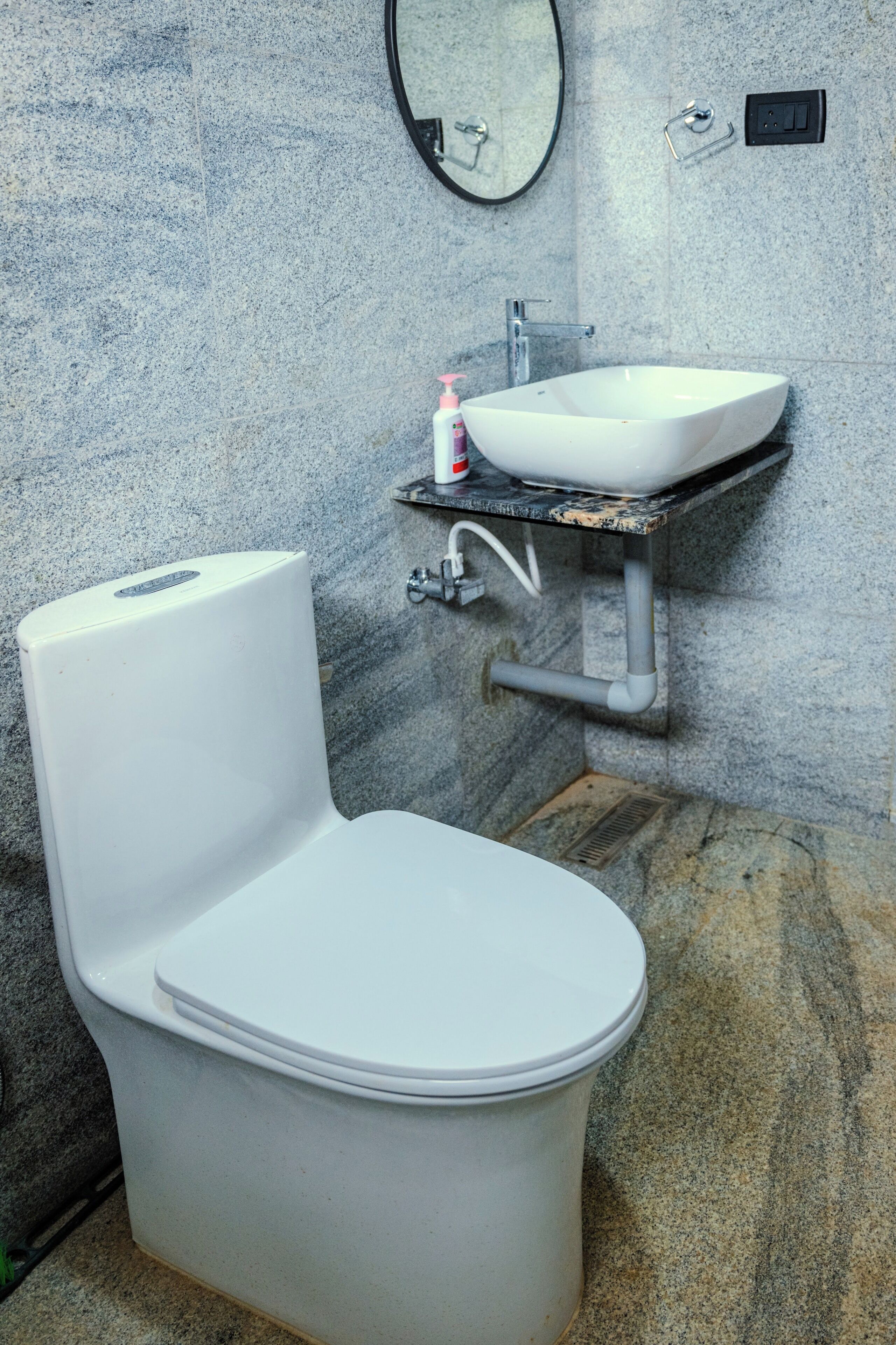 A bathroom with a white toilet, a white sink, and a mirror on the wall.