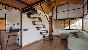Un interno moderno con una scala in legno, un divano e un'area pranzo.