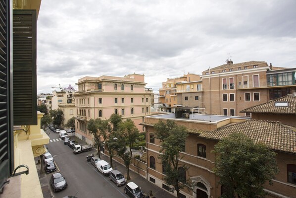 Vista de una calle con edificios, coches aparcados y árboles.