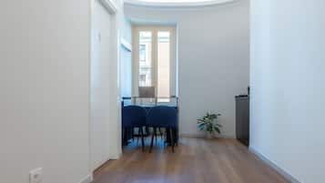 Un pasillo estrecho con una zona de comedor que incluye dos sillas azules y un ordenador portátil sobre una mesa.