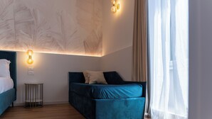 Una camera da letto moderna con un letto, un divano, un tavolino e una lampada a parete.