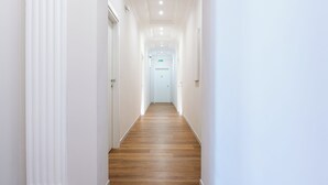 Un pasillo con paredes blancas y suelo de madera que conduce a una puerta marcada con el número 6.