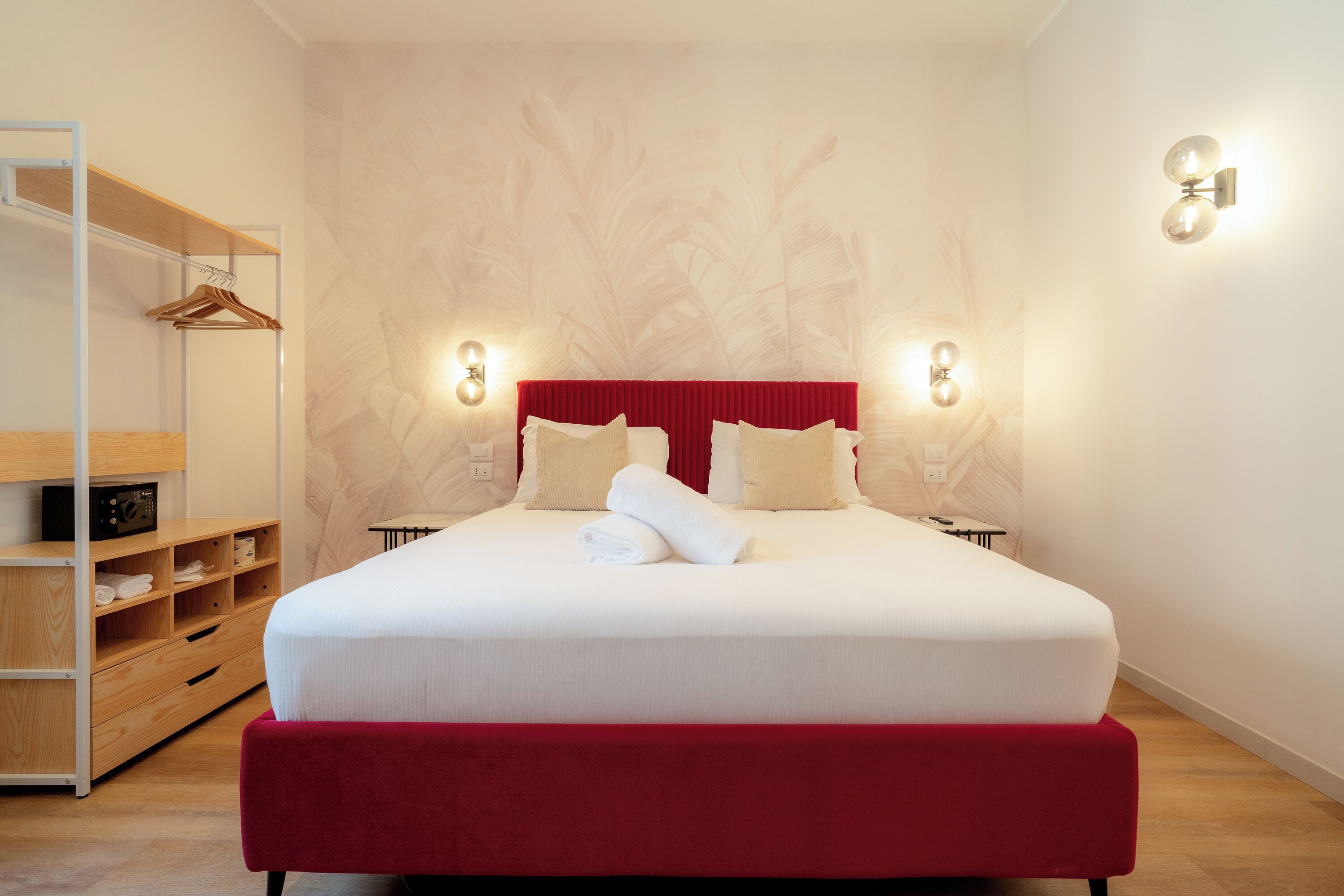 Une chambre d’hôtel avec un grand lit, une armoire en bois et une tête de lit rouge.