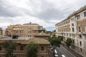 Un edificio de varios pisos con techo de tejas, ventanas grandes y una calle al frente.