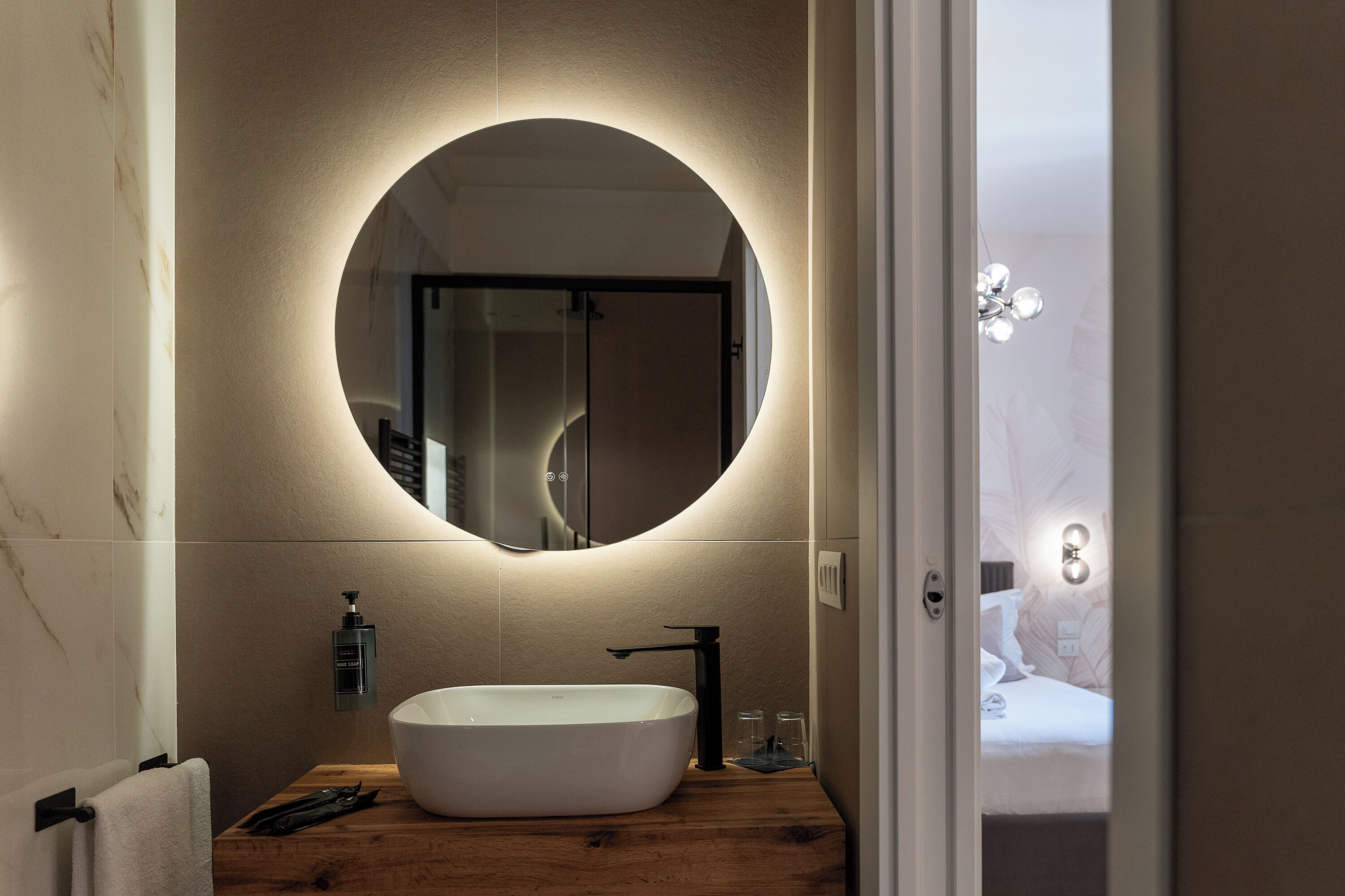 Un baño moderno con un espejo redondo, una bañera blanca y un tocador de madera.