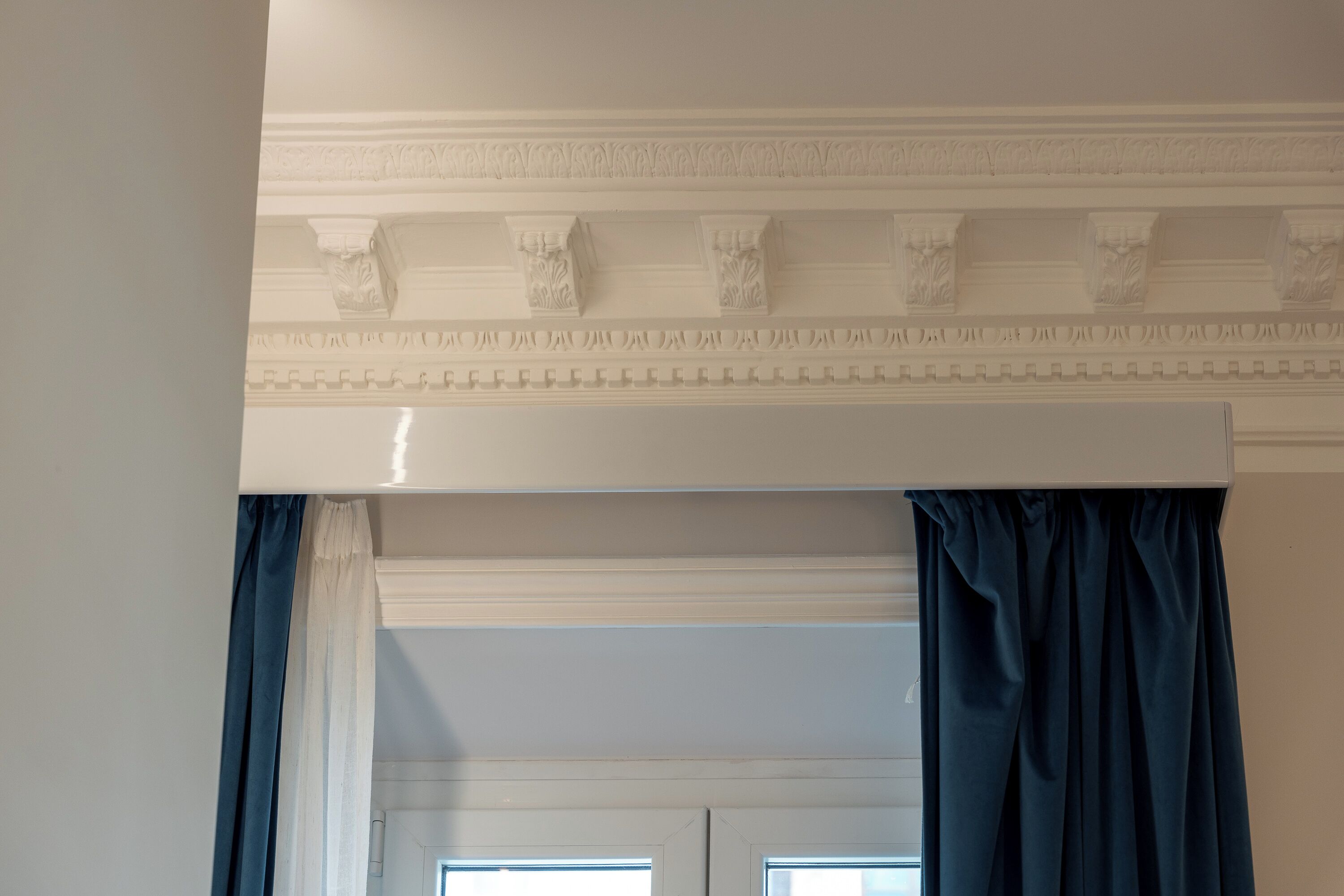 A room with a white ceiling, a decorative molding, a window with a view, and dark curtains.