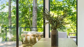 Een kamer met een groot raam, een houten tafel en een vaas met groene planten.