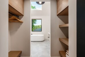 A modern bathroom with a bathtub, wooden shelves, and a window with a landscape view. - Luxury Couples Cabin in Hocking Hills, Ohio with private hot tub and outdoor fireplace on covered private balcony with forest views. (New Plymouth)
