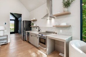 Eine moderne Küche mit Edelstahlgeräten, einem großen Fenster und Blick ins Freie.