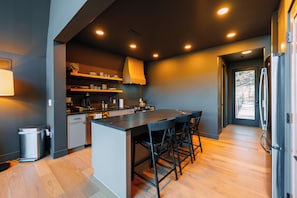 A modern kitchen with a central island, bar stools, and built-in appliances.