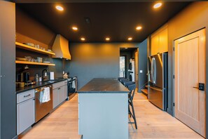 Una cocina moderna con una isla central, electrodomésticos integrados y vistas al área de lavandería contigua.