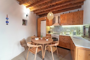 Una cocina con armarios de madera, una mesa redonda de madera y una lámpara colgante.