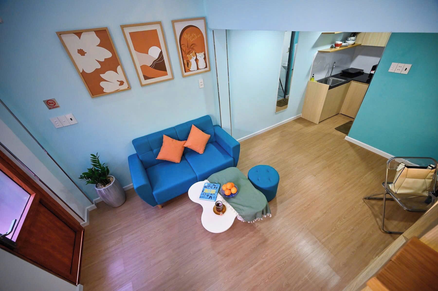 Ein gemütlicher Wohnbereich mit einem blauen Sofa, einem kleinen runden Tisch und einer Küchenzeile.