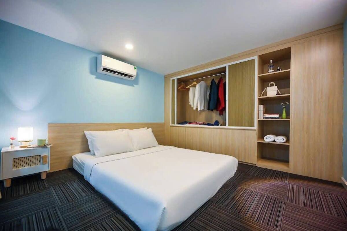 A hotel room with a bed, a wardrobe, a nightstand, and an air conditioning unit.