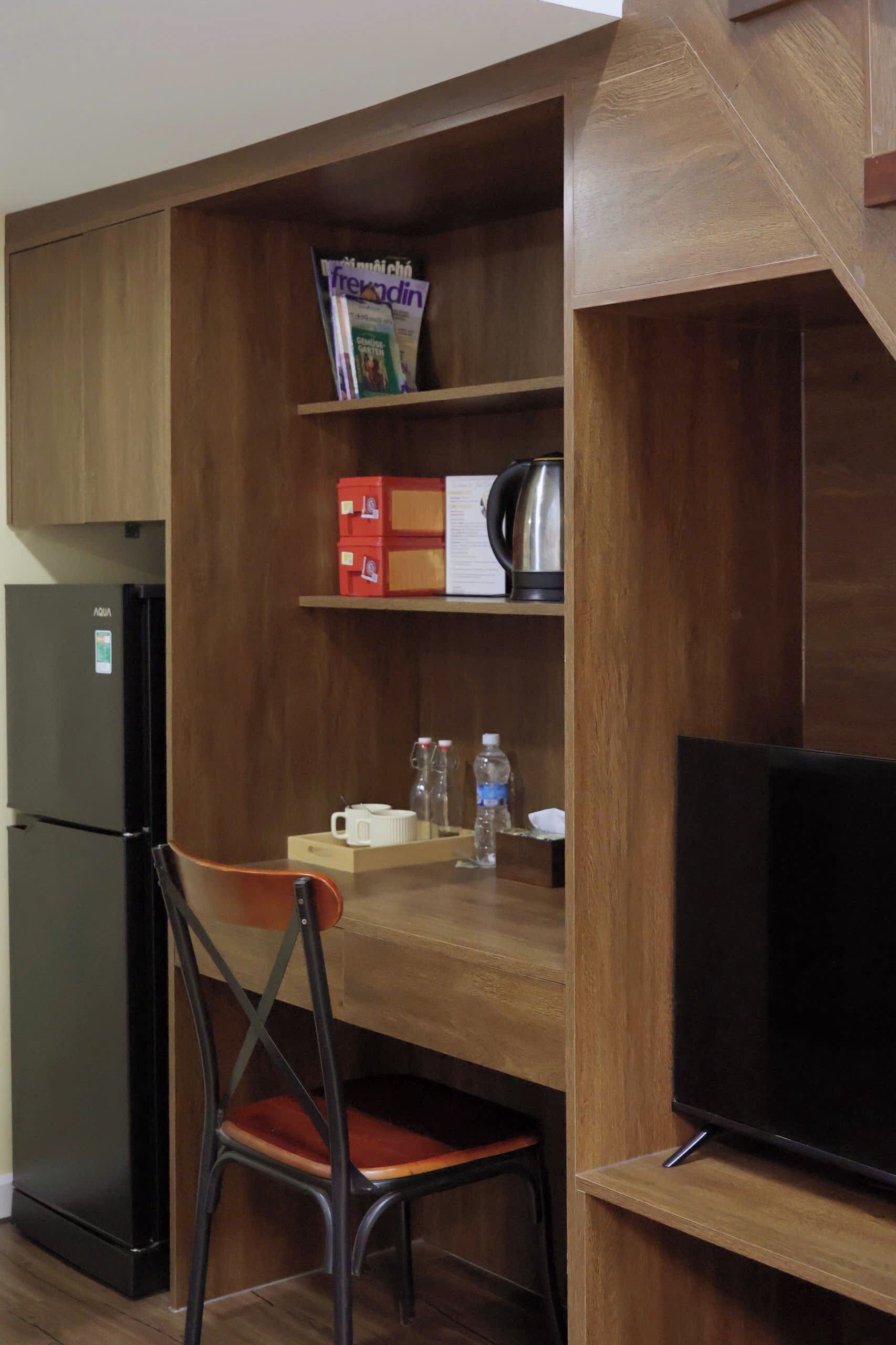 Eine kleine Küchenzeile mit Kühlschrank, Kaffeemaschine und einem Stuhl.